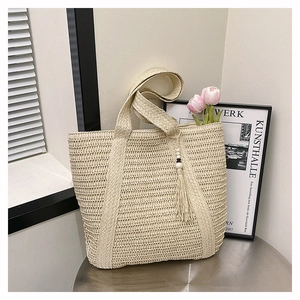 Detail of hollow-out straw weave texture and wooden bead tassel on cream tote bag