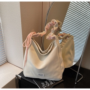 Detail view of cream tote bag with pink and green pleated handles and drawstring accents