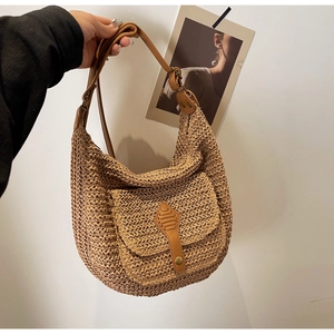 Detailed macro view of woven straw shoulder bag with leather flap pocket and metal buckle