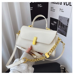 Detail of creamy white leather handbag featuring gold metal buckle and chunky chain strap