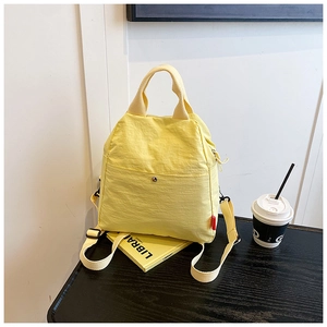 Detailed macro view of yellow multi-functional canvas sling bag on a dark wooden table