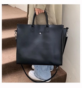 Close-up of black matte faux leather tote bag with silver rivet and adjustable strap