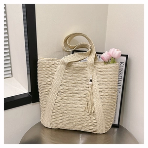 Detail of hand-woven straw tote bag with beaded tassel and dense textured weaving