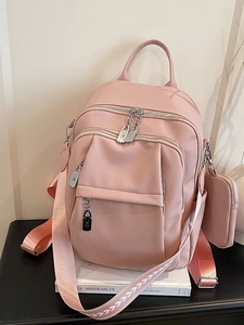 Pink pebbled leather backpack with woven strap and matching small pouch on a table