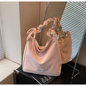 Pink slouchy tote bag with ruffled handle and side ribbon bow detail in a cozy setting