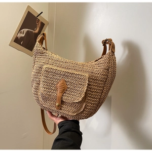 Detail of hand-woven straw shoulder bag with leather pocket and adjustable brown strap