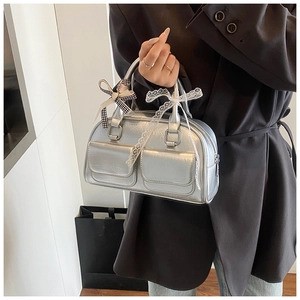 Silver mirror bowling bag with multi-pockets and decorative bow charms held by model