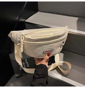 Dettaglio della borsa a tracolla crema con finitura perlata e chiusura a zip liscia