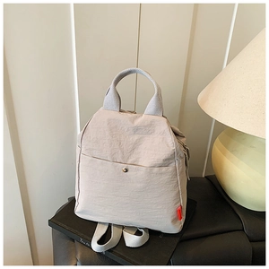 Detail view of cream nylon chest bag with wrinkled texture, metal buckle, and red label