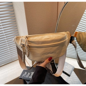 Detail of beige canvas crescent moon waist bag featuring an embroidered logo and rope pullers