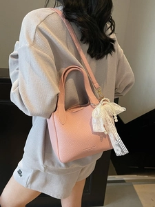 Pink lychee texture leather bucket bag with lace pearl charm accessory on model