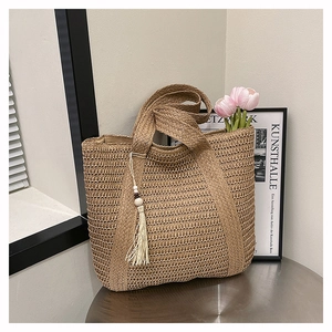 Detail of hand-woven straw tote bag with wood beads and tassel in natural sunlight