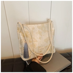 Detail of off-white bucket bag with golden butterfly embroidery and grey silk tassel