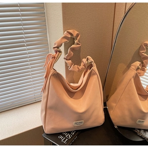 Detail of soft pink faux leather tote bag with pleated handle and tassel charm