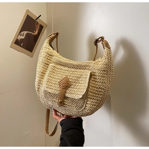 Close-up of hobo straw bag featuring a brown leather flap pocket and woven texture