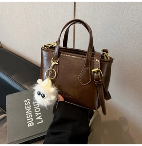 Détail du sac seau en cuir PU marron avec un pendentif monstre en peluche blanc mignon