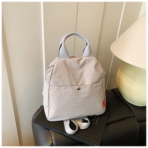 Detail of multi-functional light grey chest bag on books with warm ambient lighting