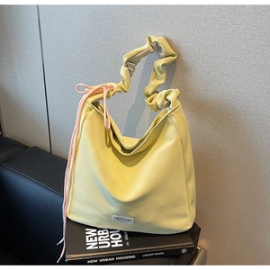 Detail of light yellow pleated handbag featuring soft leather texture and pink drawstring