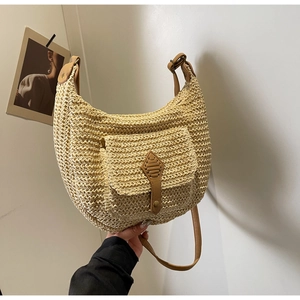 Detail of hand-woven straw crossbody bag with brown leather strap and front pocket
