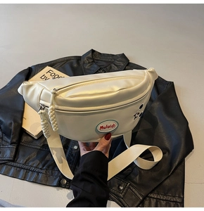 Dettaglio borsa a tracolla in pelle bianca con etichetta rossa e tirazip in corda intrecciata
