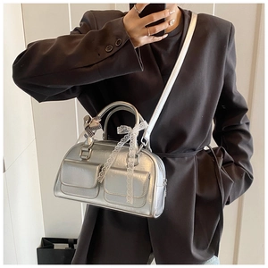 Silver metallic bowling bag with multi-pocket design and lace bow worn over a grey blazer
