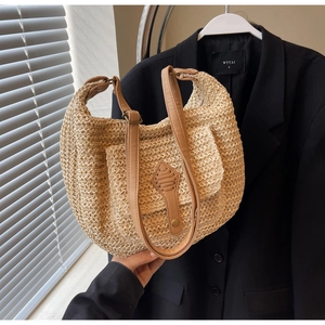 Detail of handwoven beige hobo bag with brown leather strap and geometric trim