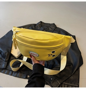 Dettaglio del marsupio giallo cartoon con ricamo del viso e logo su giacca di pelle