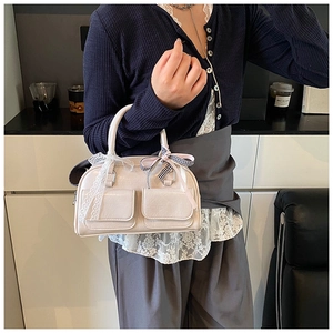 Close-up of beige bowling bag with front pockets and checkered lace bow detail