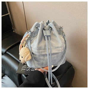 Detail of light blue drawstring bucket bag with cute beige puppy plush keychain accessory