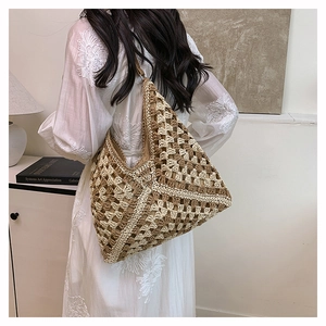 Close-up of bohemian woven straw tote bag with geometric cutout patterns and hobo style
