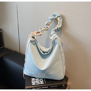 Detail of light blue hobo bag with unique ruched strap and decorative pink drawstring accents