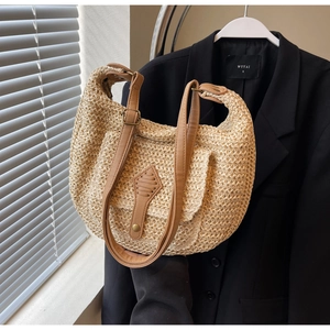Detail of straw woven bag featuring a brown leather strap and magnetic snap closure