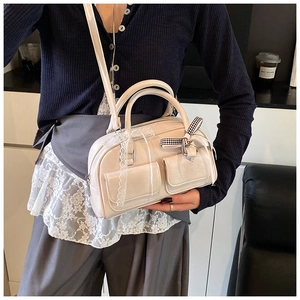 Detail of cream boston bag featuring lace trim and checkered bow on front pockets