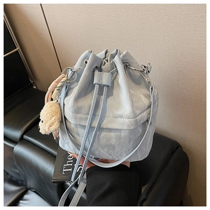Close-up of light blue drawstring bucket bag with a cute plush dog charm accessory