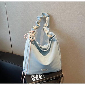 Detail of light blue tote bag with ruched handle and decorative pink drawstring side accents