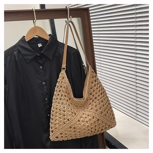 Detail view of woven straw tote bag featuring leather shoulder straps and fabric lining
