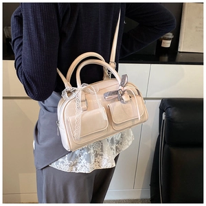 Detail of cream bowling bag showing lace bows, plaid ribbons, and front flap pockets