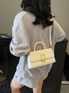 Sac à bandoulière minimaliste en cuir blanc avec boucle dorée porté par un mannequin