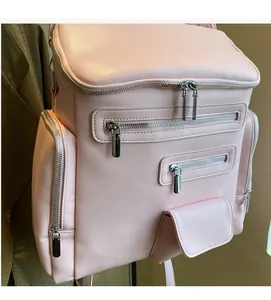 Detail of light pink PU leather backpack featuring silver metal zippers and multi-pocket design