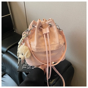 Detail of pink drawstring bucket bag with soft PU leather texture and plush dog pendant