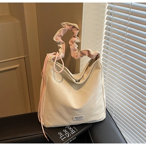 Detail of cream leather shoulder bag featuring pink ruched handle and side drawstring