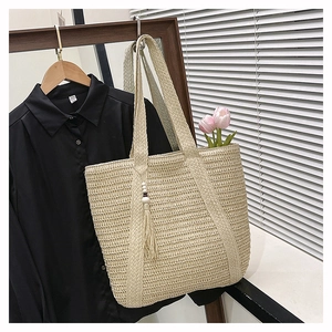 Detailed weave of cream straw tote bag with elegant white beaded tassel charm
