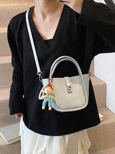 Light gray bucket bag with silver buckle and cute charm on stairs