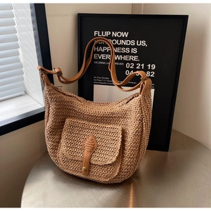 Detail view of woven straw beach bag featuring leather front pocket and brass buckle