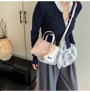 Sac seau rose avec breloque monstre en peluche porté par un mannequin en intérieur