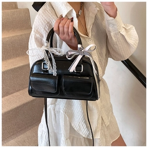 Detail of black bowling bag showing front pockets and ribbon bow ornaments