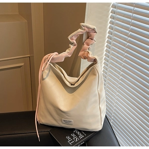Detail of cream shoulder bag with pink ruffled strap and metallic MULAIDI logo plate