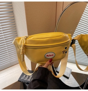 Dettaglio del borsupio giallo con tracolla regolabile e trama della toppa ricamata