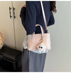Détail du sac seau en cuir rose avec charm agneau en peluche blanc porté à l'épaule