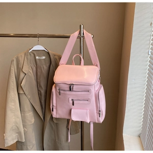 Detailed view of pink multi-pocket backpack on hanger with a stylish trench coat